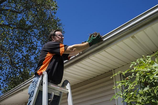 a repair technician inspecting a damaged gutter for necessary repairs in Amlin